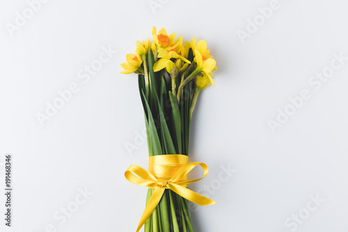 beautiful blooming daffodils flowers with yellow ribbon isolated on grey