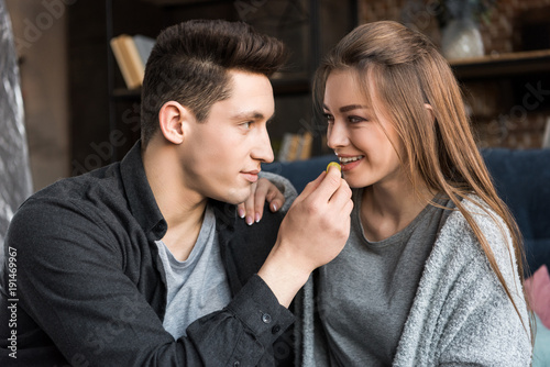 boyfriend feeding happy girlfriend with grape