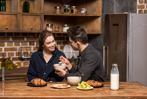 boyfriend asking girlfriend to taste breakfast in kitchen