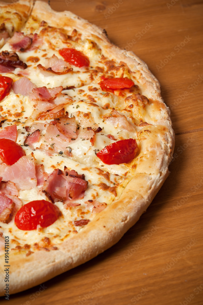 Delicious Italian pizza with ham, cherry tomatoes and parmesan on wooden table. Top view
