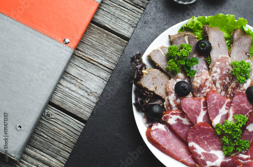 nicely sliced meat on plate, on wooden background in rustic style