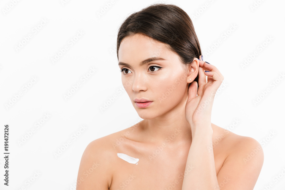 Beauty portrait of beautiful asian woman looking aside with cream on her body, isolated over white background