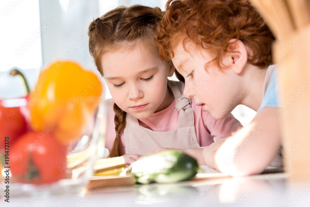 focused children reading cookbook while cooking together in kitchen