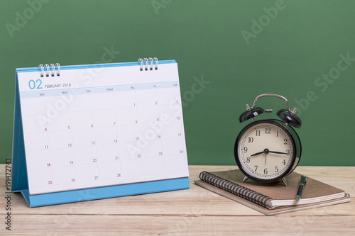 Vintage clock and book  with calendar February on wood, time concept