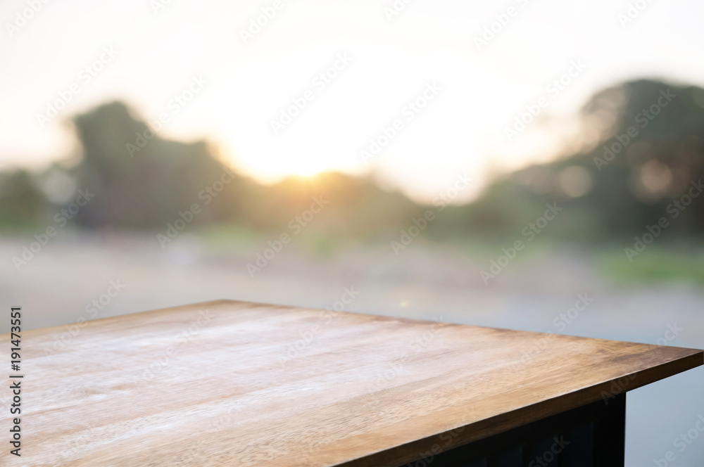 empty wooden desk over blurred montage home garden with sunset background