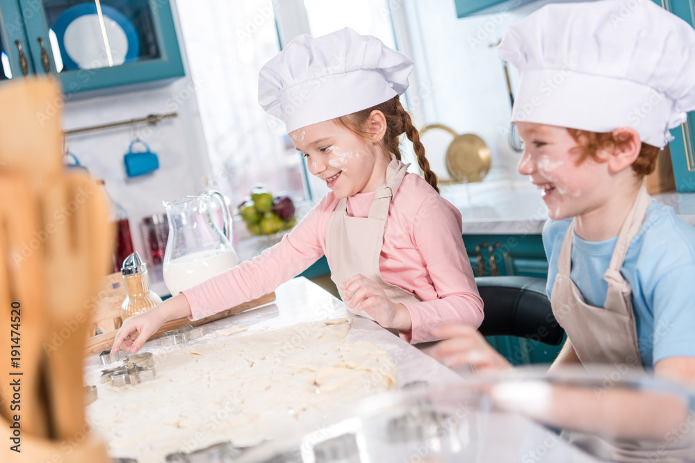 happy little children in chef hats preparing cookies together in kitchen happy little children in chef hats preparing cookies together in kitchen