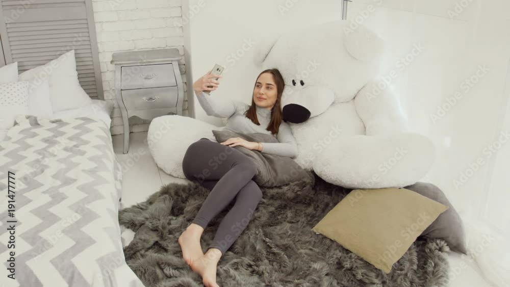 Young caucasian women making self-portrait with teddy bear in white room Young caucasian women making self-portrait with teddy bear in white room