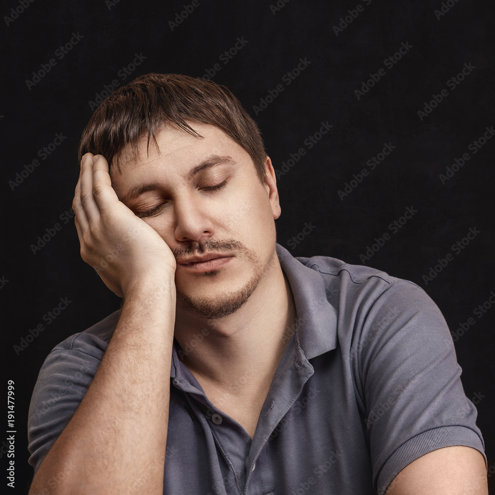 A man with closed eyes leans on his arm A man with closed eyes leans on his arm