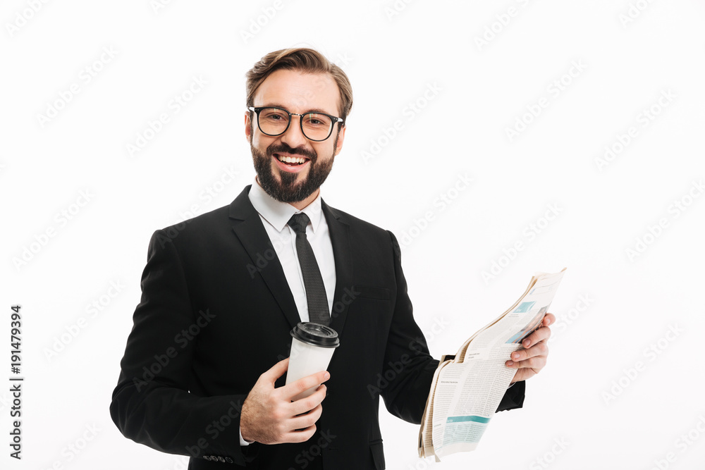 Portrait of cheerful male employer in suit and eyeglasses smiling while drinking takeaway coffee and reading newspaper, isolated over white wall Portrait of cheerful male employer in suit and eyeglasses smiling while drinking takeaway coffee and reading newspaper, isolated over white wall