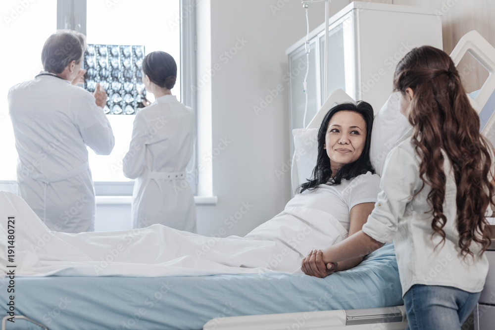 Do not worry honey. Cheerful mature lady smiling while lying in a hospital bed and talking to her adorable daughter during her family visit. Do not worry honey. Cheerful mature lady smiling while lying in a hospital bed and talking to her adorable daughter during her family visit.