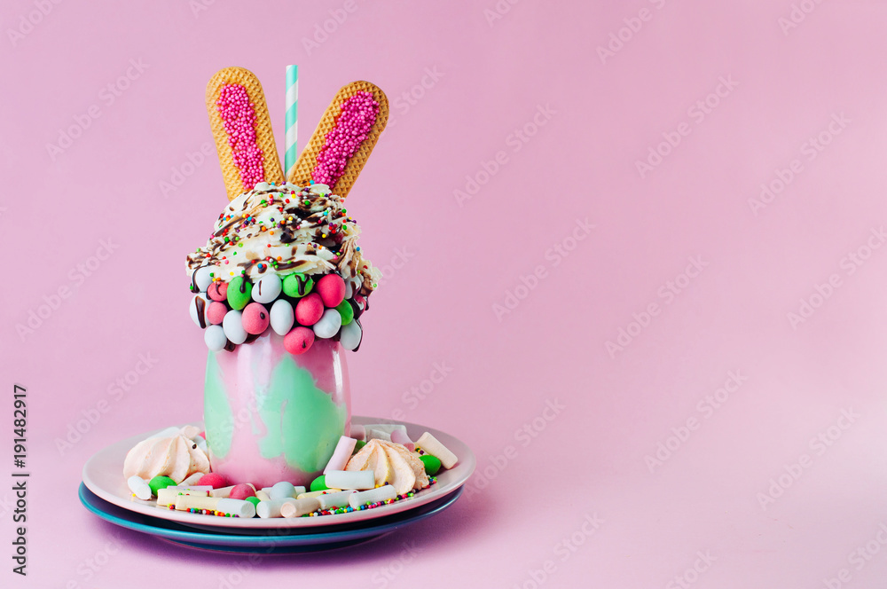 Easter freak shake decorated with bunny ears cookies on pink background with copy space