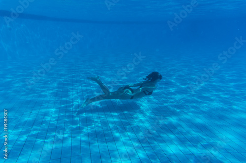 Young woman portrait wearing bikini underwater in swimming pool. Vacation, fun, lifestyle concept.