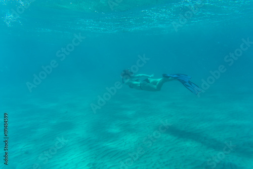 Young woman snorkeling over coral reef in the tropical sea.