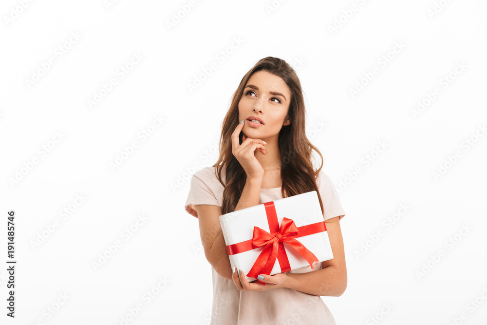 Pensive brunette woman in t-shirt holding gift and looking up Pensive brunette woman in t-shirt holding gift and looking up
