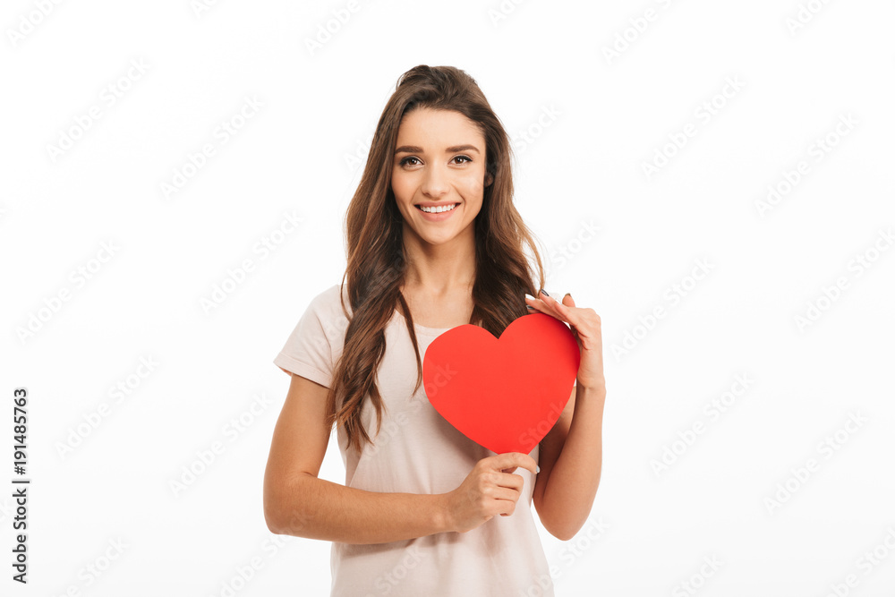Smiling brunette woman in t-shirt holding paper heart Smiling brunette woman in t-shirt holding paper heart