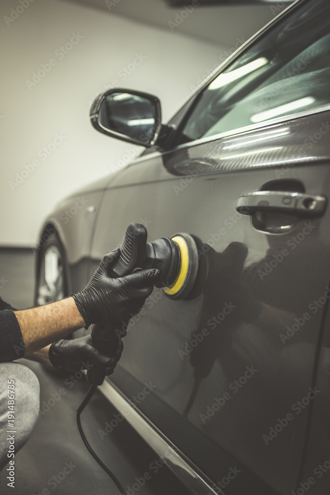 Car detailing - Worker with orbital polisher in auto repair shop. 