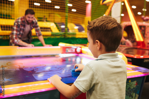 Happy little boy playing air hockey with his dad © Drobot Dean
