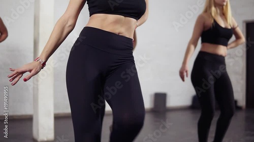 Sportive bodies of female dancers in black active wear learning bachata moves. Groovy, fun, fitness photo