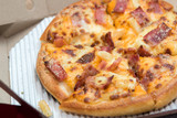 Close up of pizzas with variety of toppings and cheese in cardboard take out boxes with open lid