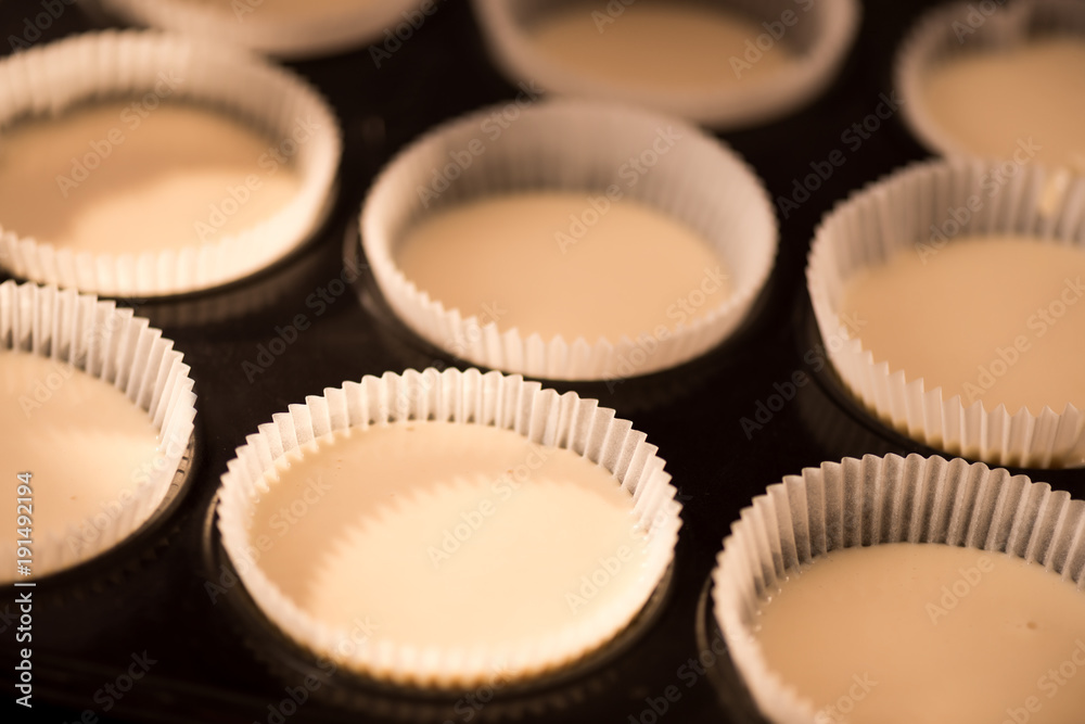 close up view of baking forms with raw dough for cupcakes close up view of baking forms with raw dough for cupcakes