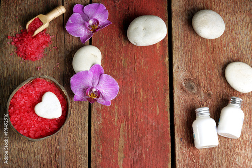 Spa still life for St. Valentine's Day in red and white colors with orchid flowers and massage stones, top view, copy space for your text