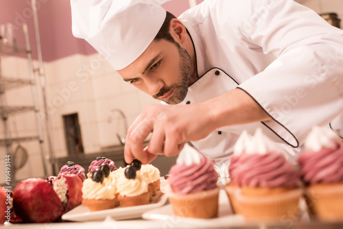 confectioner decorating cupcakes in restaurant kitchen photo