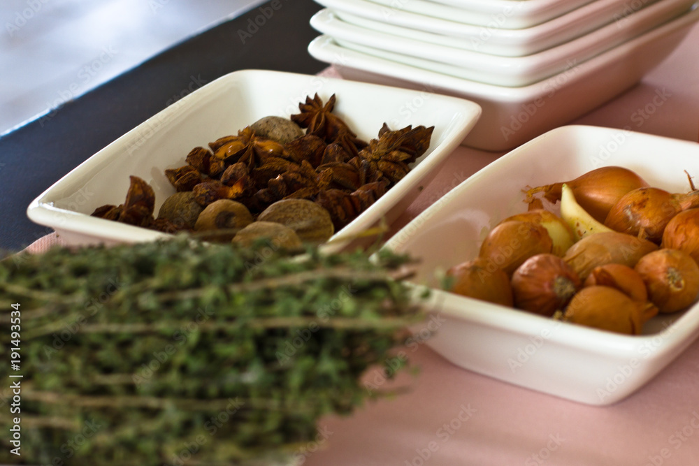 Dried anise and thyme, small onions in white bowls Dried anise and thyme, small onions in white bowls