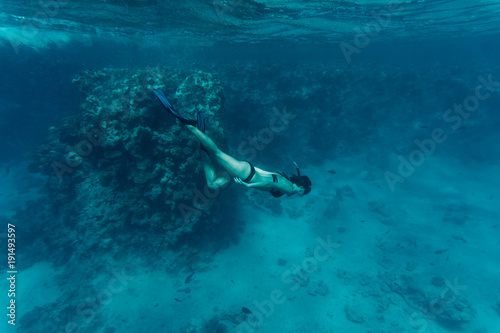 Underwater beaty woman in bikini snorkeling in a clear tropical water at coral reef photo