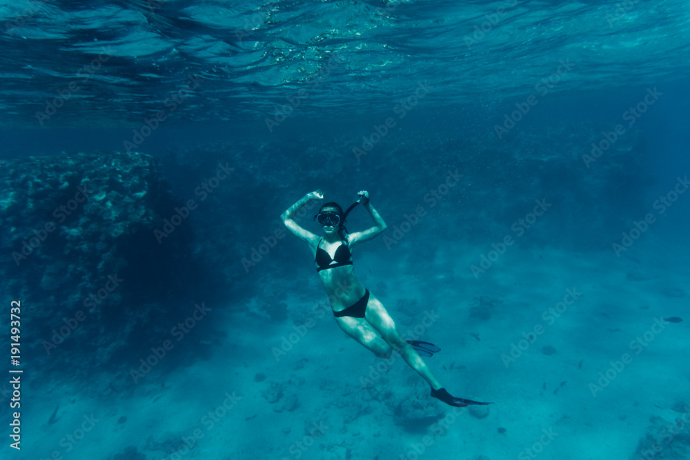 Young woman diving on a breath hold by a coral reef sea