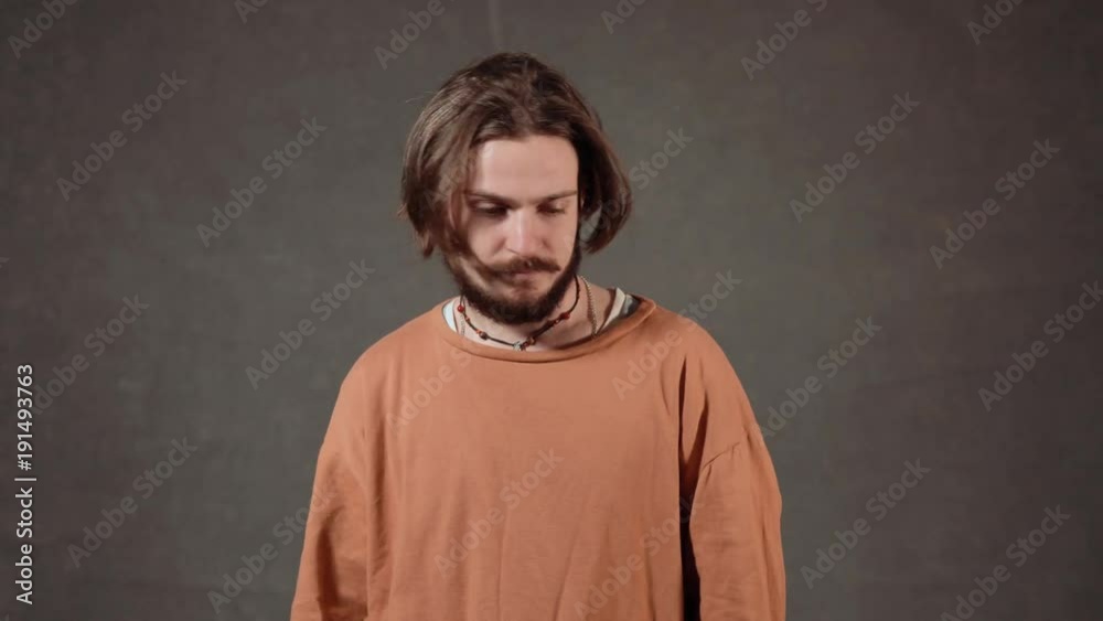 Stressed boy with a dark beard looking nervously, portrait shot in the gray background Stressed boy with a dark beard looking nervously, portrait shot in the gray background