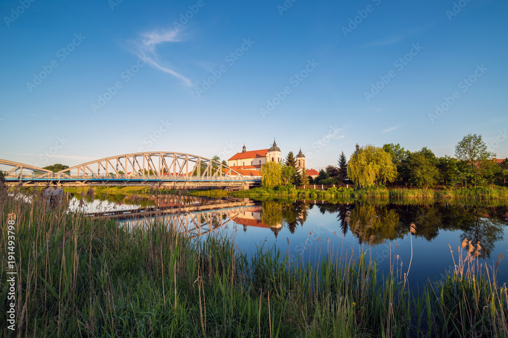 Obraz premium View at bridge over the Narew river and baroque Church of the Holy Trinity in Tykocin town, Podlasie, Poland