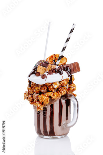 Chocolate indulgent extreme milkshake with chocolate, popcorn and sweets. Crazy freakshake food trend. Isolate. photo