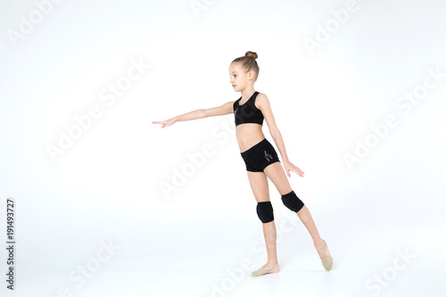 Rhythmic gymnastics caucasian ballet dancer girl in black suite stretching in black costume on white background isolated showing flexible fitness