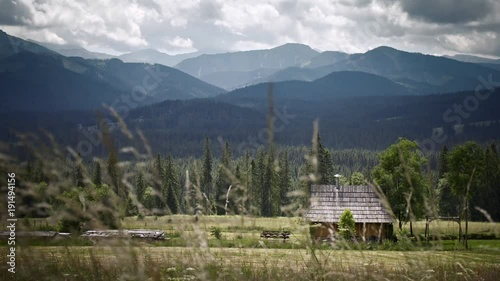 Timelaps of mountains with the hut. Grass fluttering in the wind in the foreground. 4k HDR H264 photo