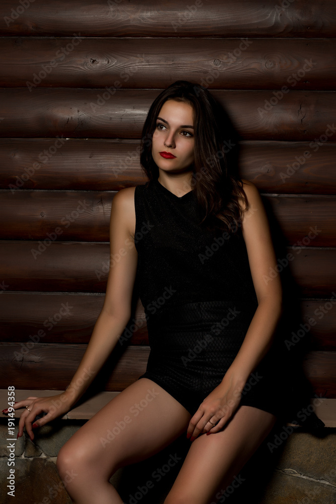 Stylish brunette model in black shirt posing at the wood background Stylish brunette model in black shirt posing at the wood background