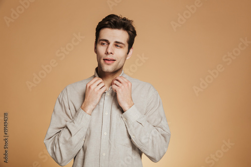 Portrait of a confident young man buttoning his shirt