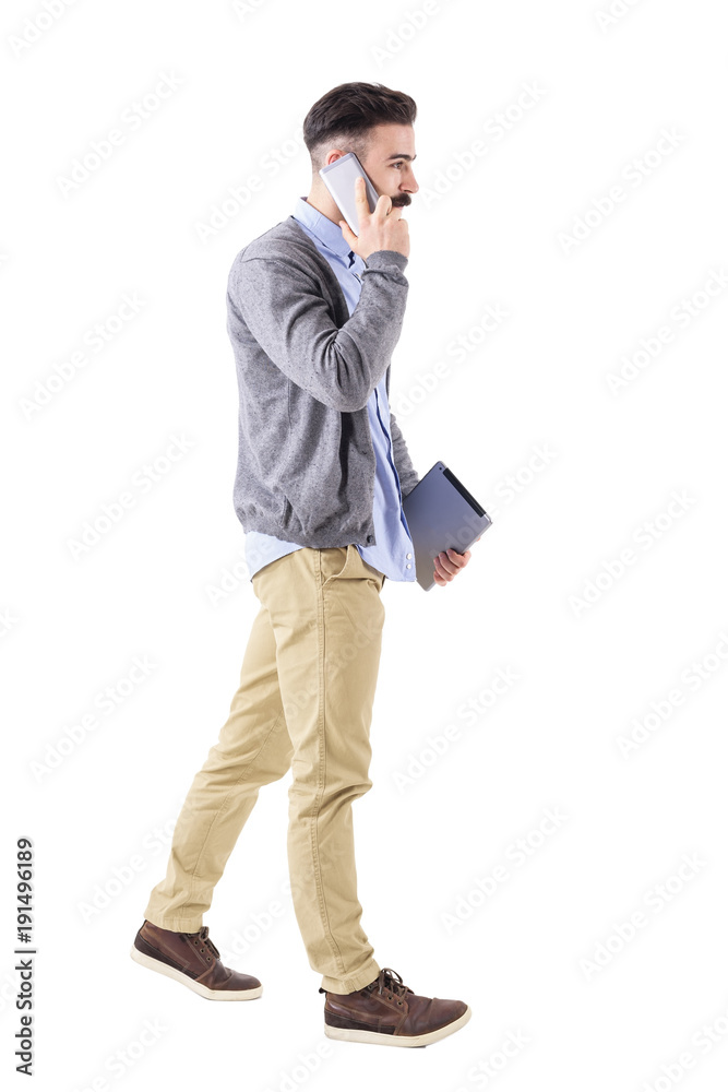 Confident young businessman with tablet on the phone, walk and look away. Full body length portrait isolated on white studio background. Confident young businessman with tablet on the phone, walk and look away. Full body length portrait isolated on white studio background.