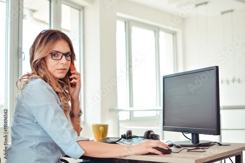 Creative woman talking on phone while sitting at desk in office © nikolaborovic88