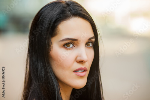 Young cute girl with long brunette hair in the street. Close up portrait