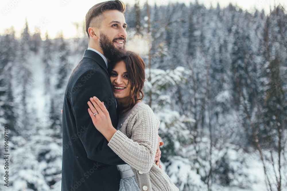 Bearded man and his lovely bride pose on the snow in a magic winter forest Bearded man and his lovely bride pose on the snow in a magic winter forest