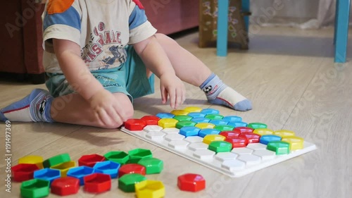 A cute child collects a picture from large multi-colored details. Playing with a puzzle
