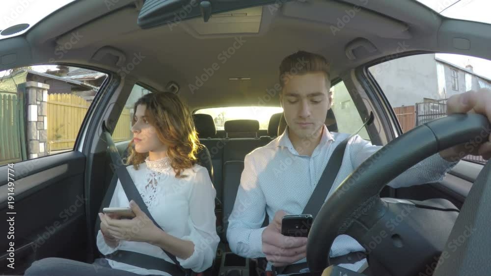 Driver and girlfriend in the car not paying attention to road both using smart phones and texting while driving 