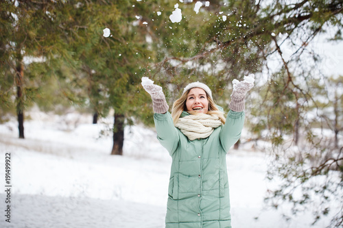 A beautiful girl throws her hands snowing up and laughing. Winter portrait of an attractive happy girl outdoors.