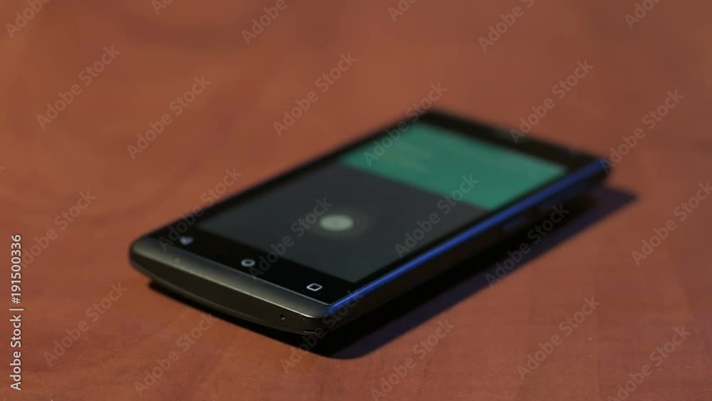 Closeup of male answering incoming call on cheap mobile phone on wooden table