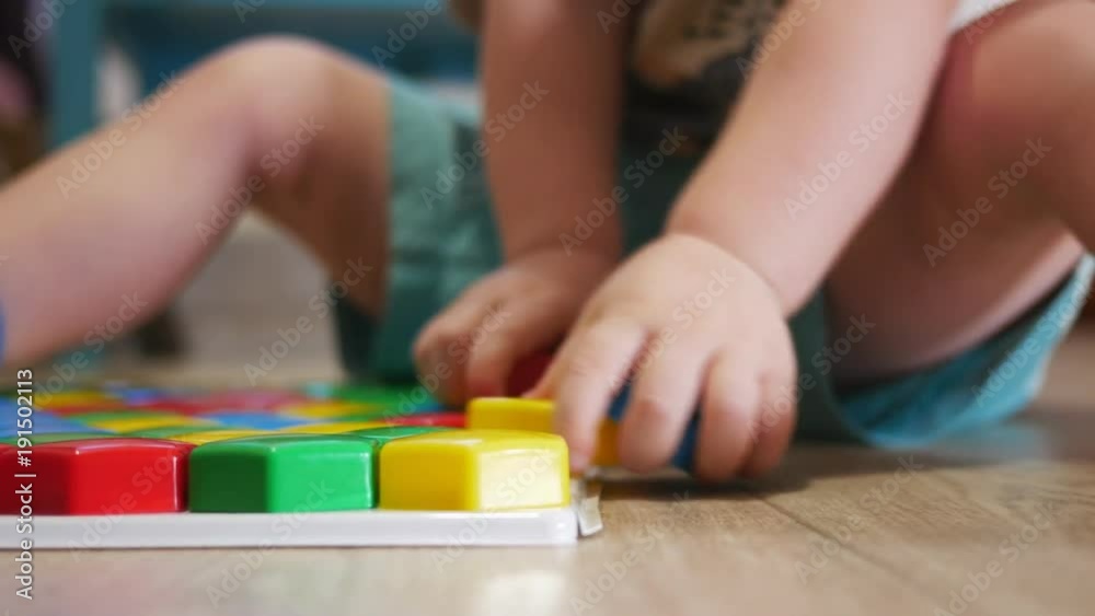 A cute child collects a picture from large multi-colored details. Playing with a puzzle A cute child collects a picture from large multi-colored details. Playing with a puzzle