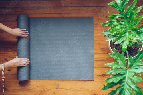 Woman rolling her mat after a yoga class, top view