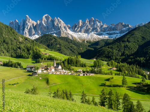 Val di Funes valley, Santa Maddalena touristic village, Dolomites, Italy, Europe. September, 2017. Green grass and blue sky. photo