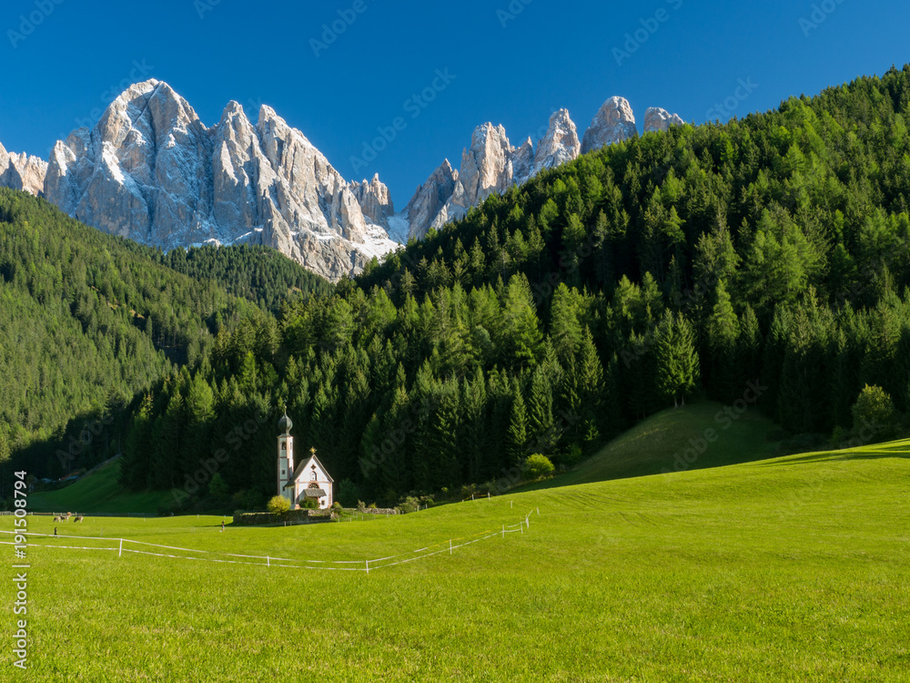 Green grass, blue sky. St Johann Church, Santa Maddalena, Val Di Funes, Dolomites, Italy. September, 2017