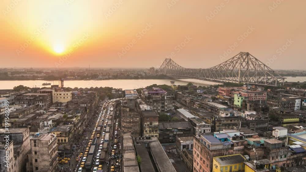 4K Timelapse of a beautiful sunset over Kolkata city with a Howrah bridge on the Ganga river, West Bengal, India.
