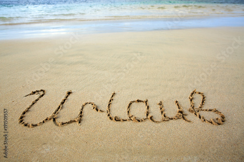Word Vacation written on the sand near the sea.